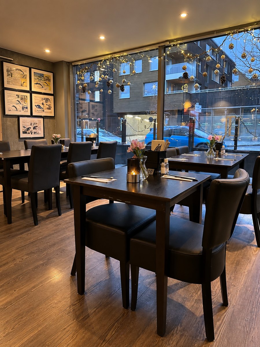 Dekkede bord i restauranten en vinterkveld, med julelys i vinduet mot Heggedal sentrum.