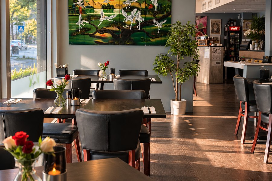 Restauranten i kveldssol, med tranemaleriet på veggen og dekkede bord.